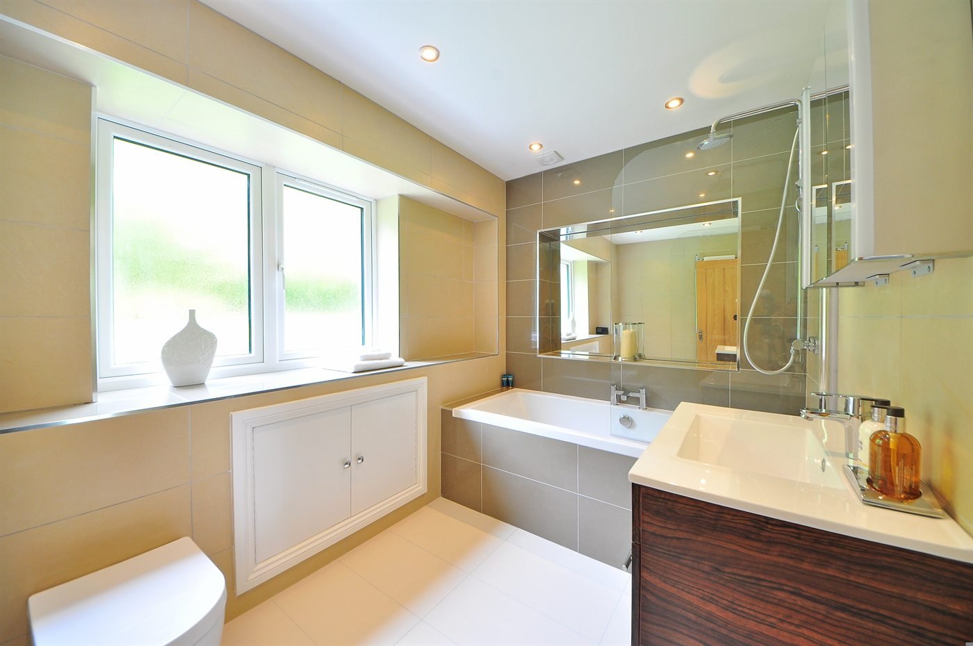 Helles Badezimmer mit Badewanne, Waschtisch und breitem Spiegel